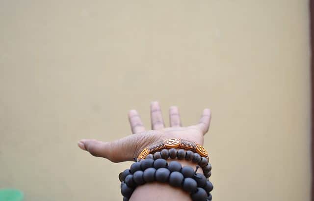 An outstretched hand wearing black and brown beaded bracelets against a plain beige background subtly mirrors the intricate layers of Country-by-Country Reporting Regulations.