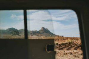 View of a rocky hill and an expansive field through the window of a vehicle on a clear day, as if the landscape itself were unbothered by Mozambique transfer pricing regulations.