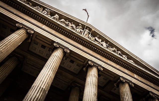 Low-angle view of a neoclassical building with tall, fluted columns and detailed sculptural frieze under a cloudy sky, reminiscent of the judicial architecture where South Africa's first transfer pricing court case was heard.