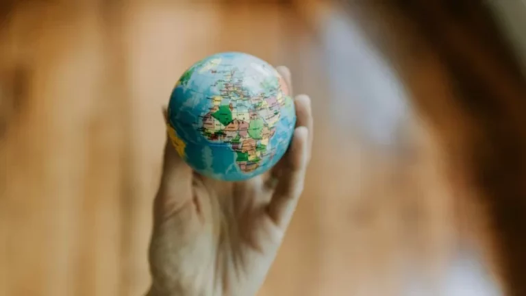 A hand holding a small globe, highlighting Africa, Europe, and the Middle East with a blurred brown background—perfect for illustrating concepts like country by country reporting or transfer pricing in global business.