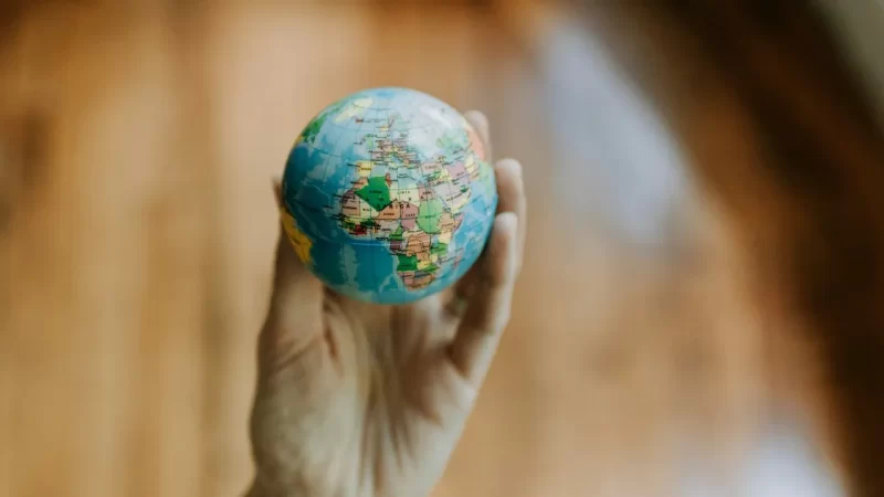 A hand holding a small globe, highlighting Africa, Europe, and the Middle East with a blurred brown background—perfect for illustrating concepts like country by country reporting or transfer pricing in global business.