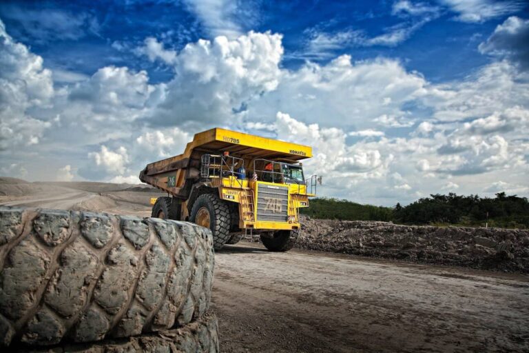 Yellow dump truck at construction site under cloudy sky.
