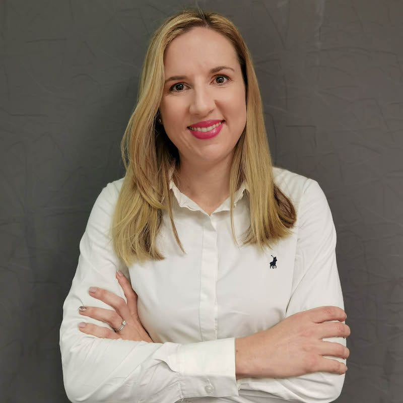 Smiling woman in white shirt with folded arms.
