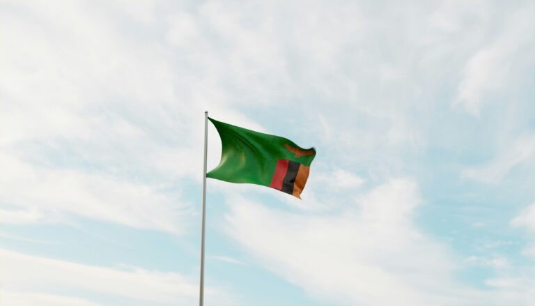 Zambian flag waving against a cloudy sky outside a courthouse hearing a case on transfer pricing